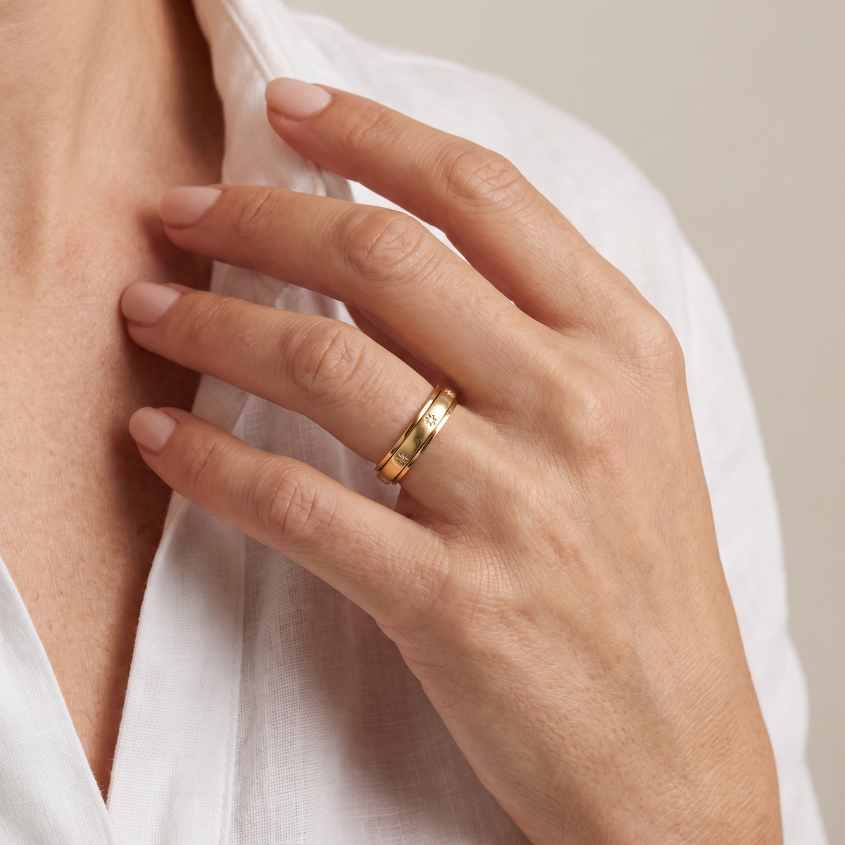 Hand at the collarbone wearing the Gold Star Spinning Ring