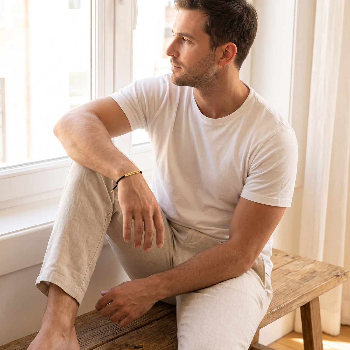 Man wearing the Hard Days bracelet, black cord with gold bar
