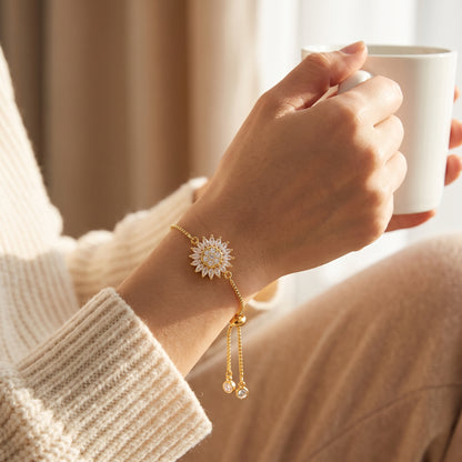 Gold sunflower spinning bracelet worn on the wrist, holding a coffee mug