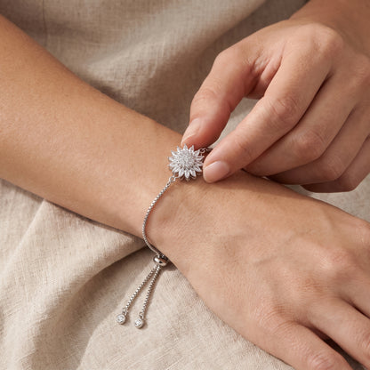 Fingers turning the silver sunflower charm of the bracelet