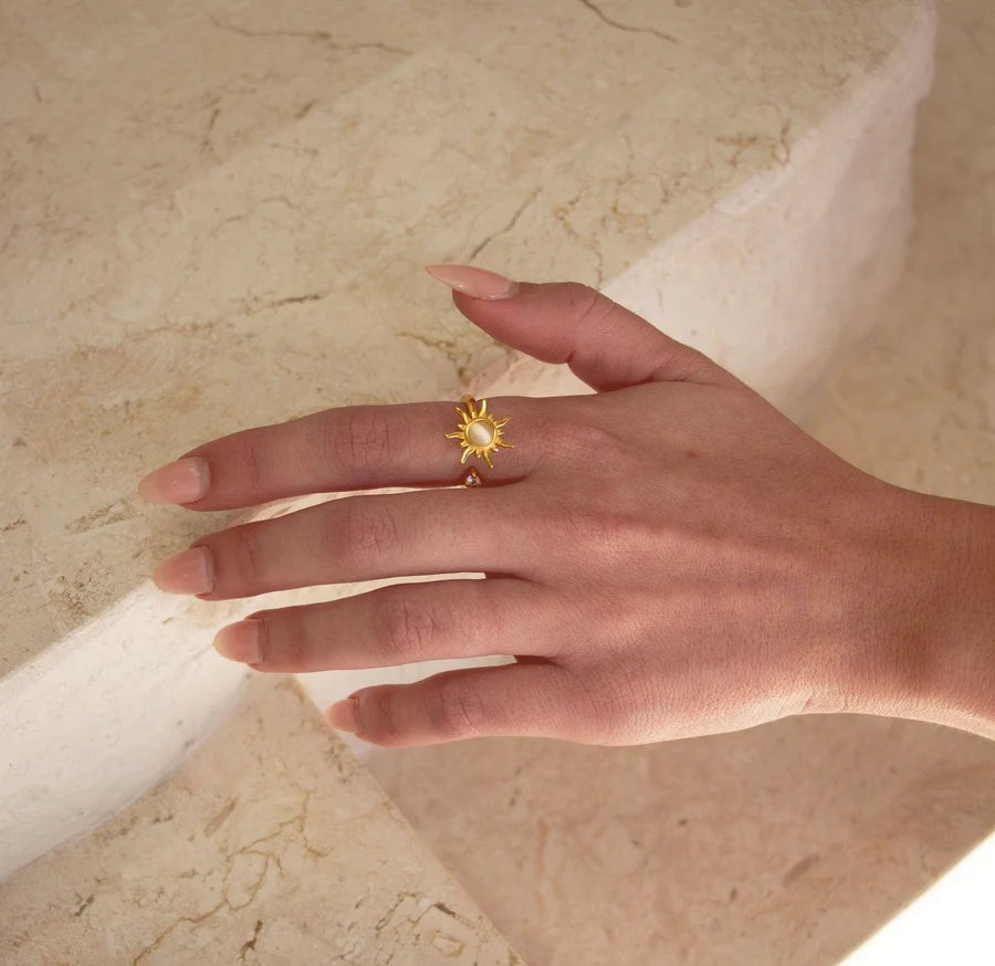 Gold sun spinner ring on a marble ledge