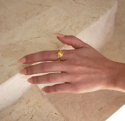 Gold sun spinner ring on a marble ledge