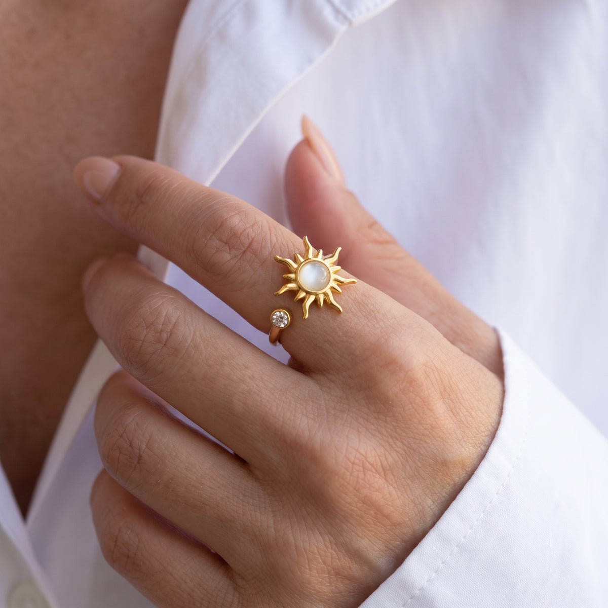 Hand against a white shirt wearing the gold sun spinner ring