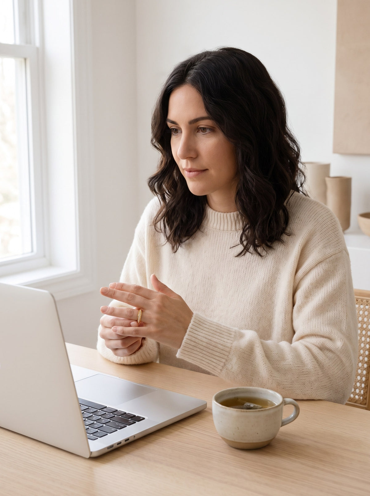 Woman calmly spinning her gold eternity ring at her desk