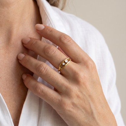 Hand at the collarbone wearing the Gold 2-Bead Hammered Ring