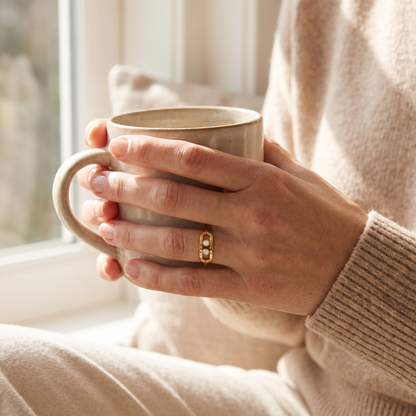 Hands holding a coffee mug, wearing the Gold 2-Bead Hammered Ring