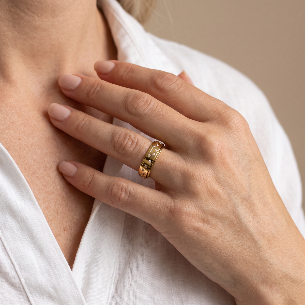 Hand at the collarbone wearing the Gold Constellation Spinning Ring