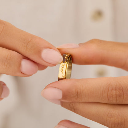 Fingers turning the gold constellation spinning ring