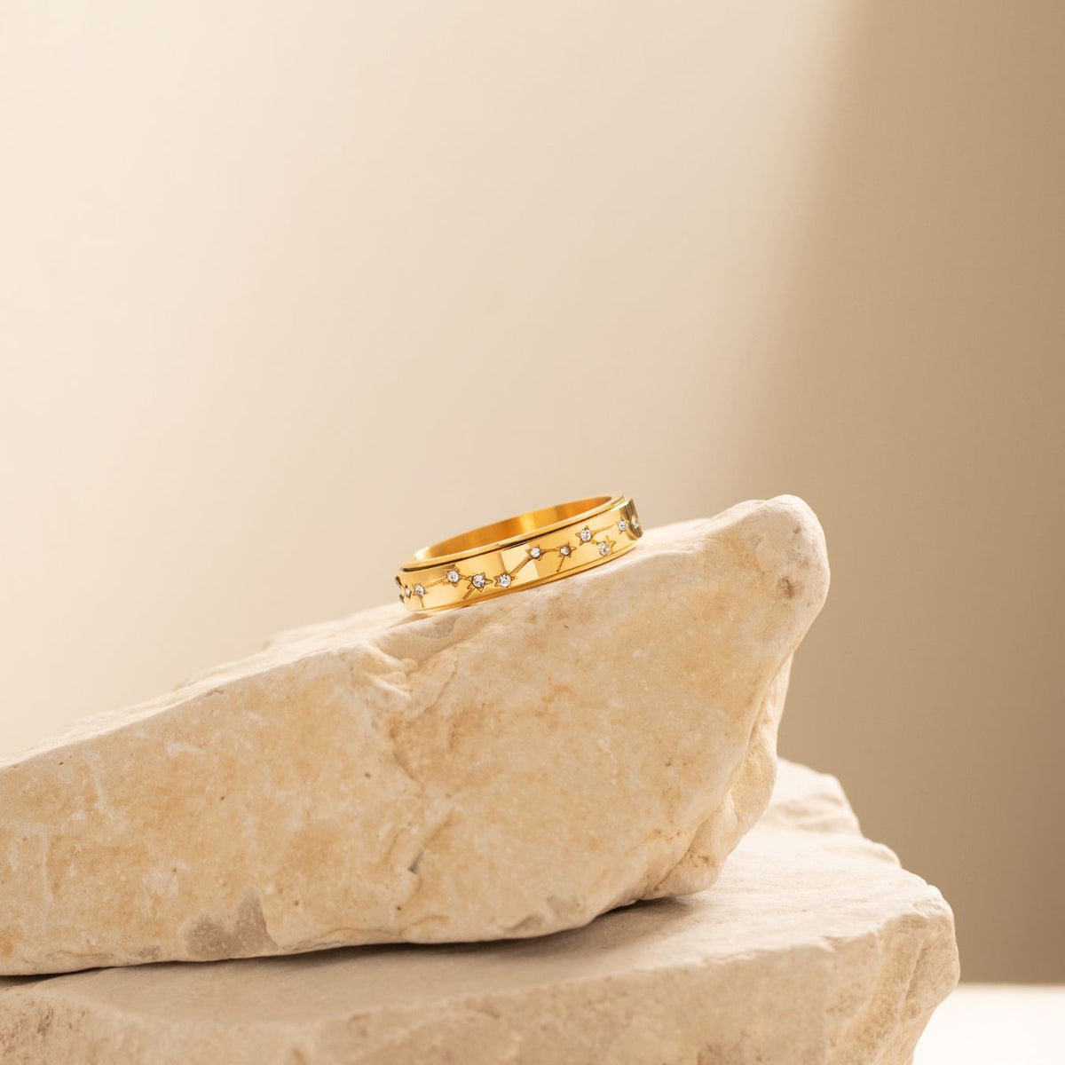 Gold constellation spinning ring resting on a stone