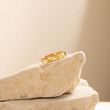 Gold constellation spinning ring resting on a stone