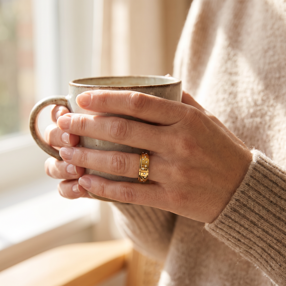 Hands holding a coffee mug, wearing the Gold Constellation Spinning Ring