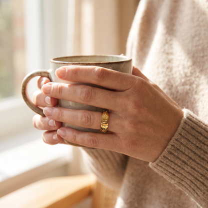 Hands holding a coffee mug, wearing the Gold Constellation Spinning Ring