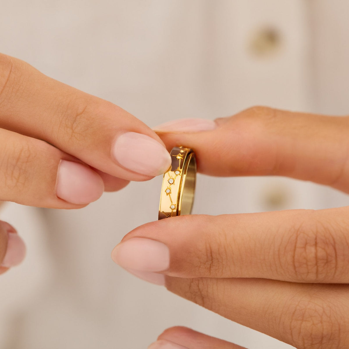 Fingers turning the gold constellation spinning ring