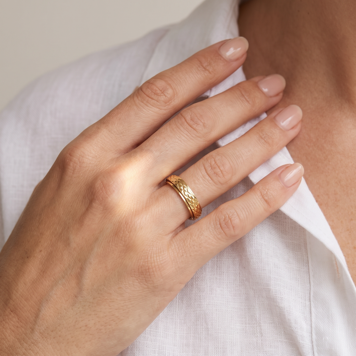 Hand at the collarbone wearing the Gold Cross Pattern Spinning Ring
