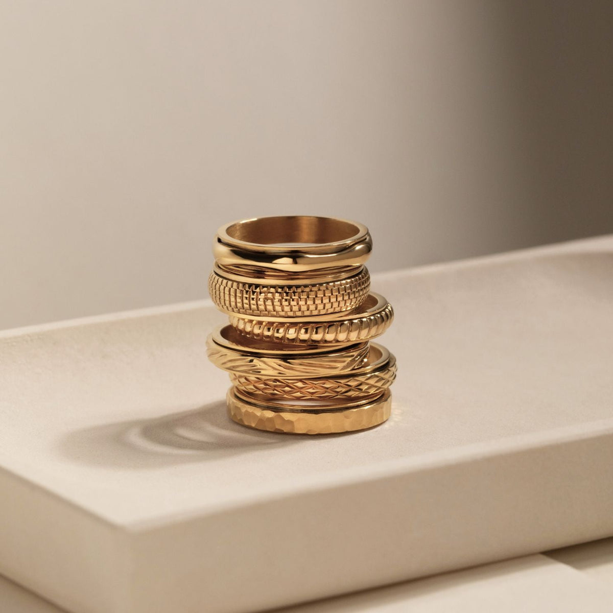 Gold cross-pattern ring stacked with other gold spinning rings