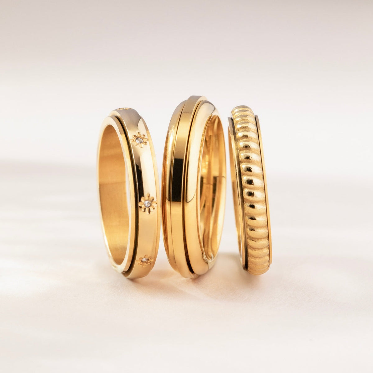 Gold star ring stacked with other gold spinning rings