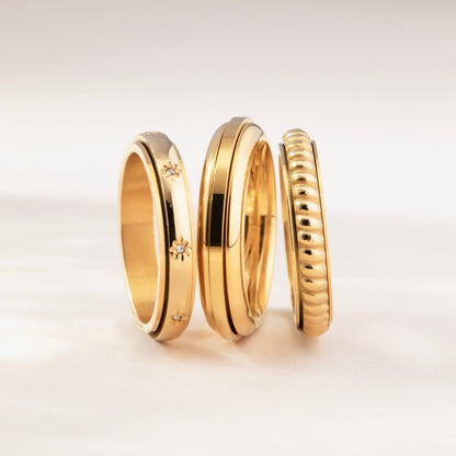 Gold star ring stacked with other gold spinning rings