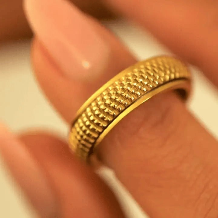 Fingers turning the gold woven spinning ring