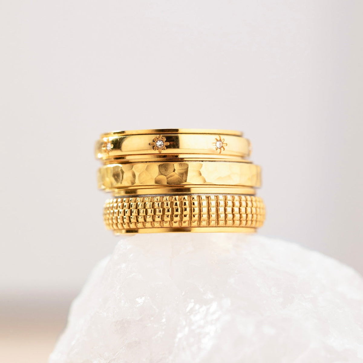 Gold woven ring stacked with other gold spinning rings