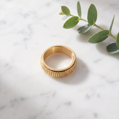 Gold Woven Spinning Ring on white marble with eucalyptus