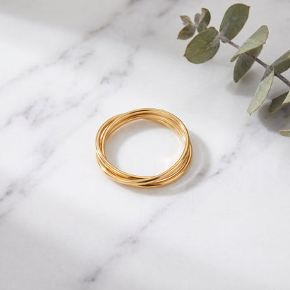Gold braided rolling ring on white marble with eucalyptus
