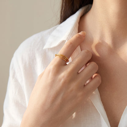 Hand at the collarbone wearing the gold three-band rolling ring