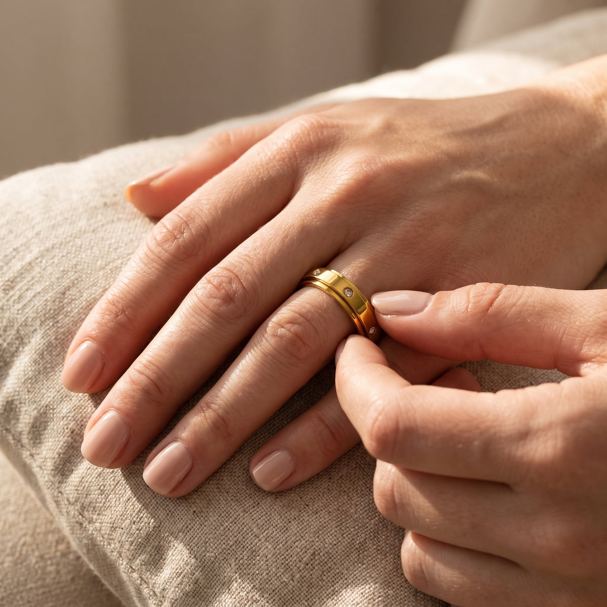 Gold spinner ring worn on the hand, thumb turning the band