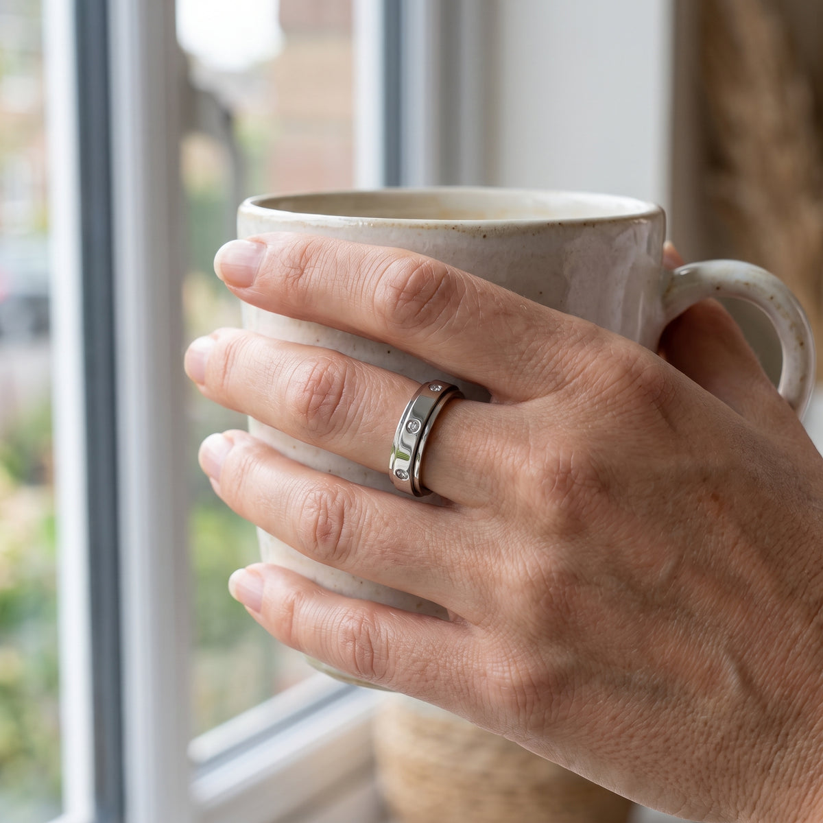 Silver spinner ring worn while holding a coffee mug