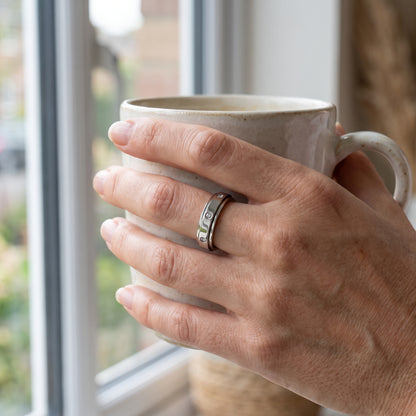 Silver spinner ring worn while holding a coffee mug
