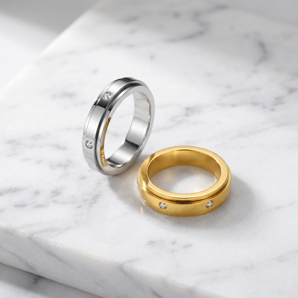 Silver and gold spinner rings on white marble