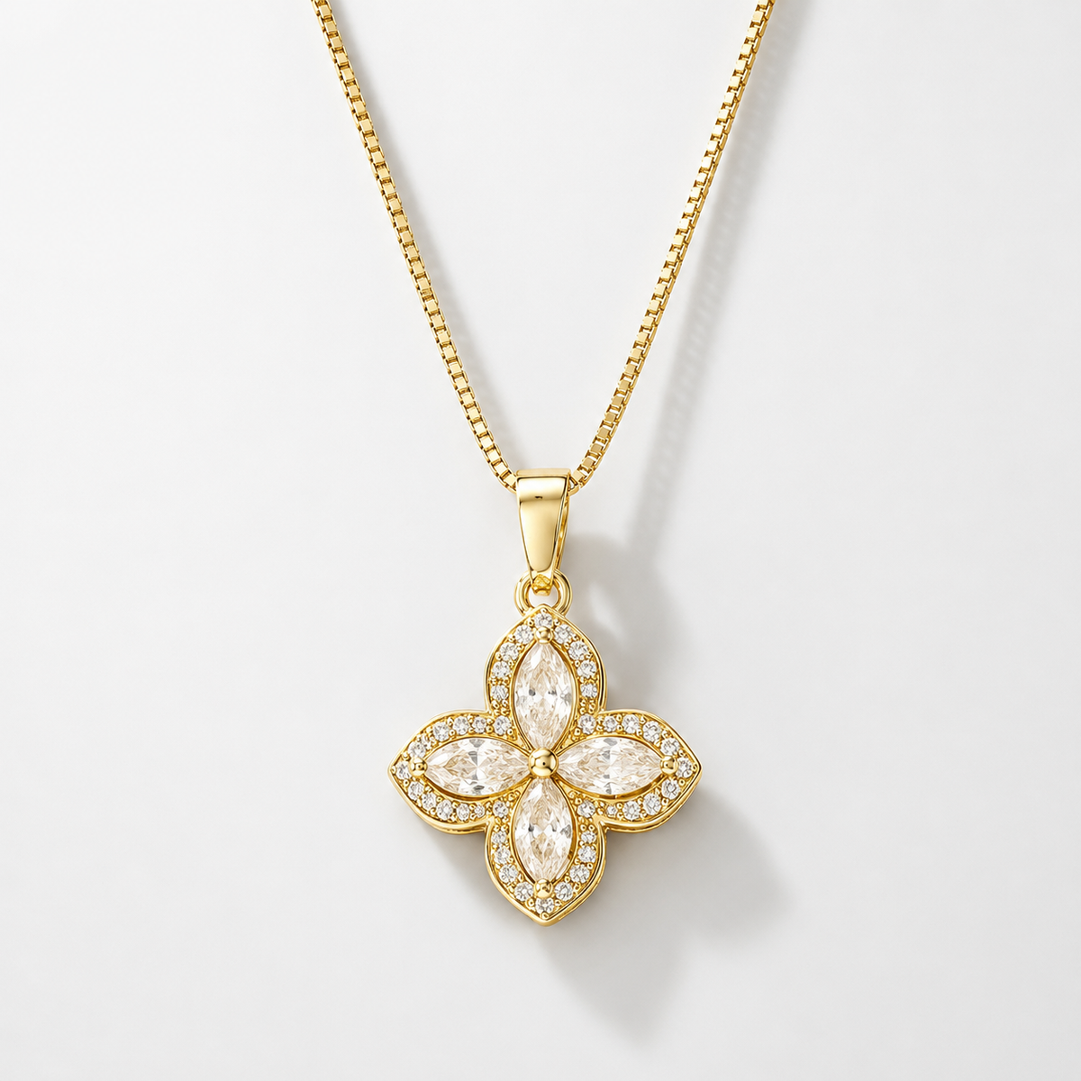 Gold four-petal flower pendant with clear crystals on a box chain