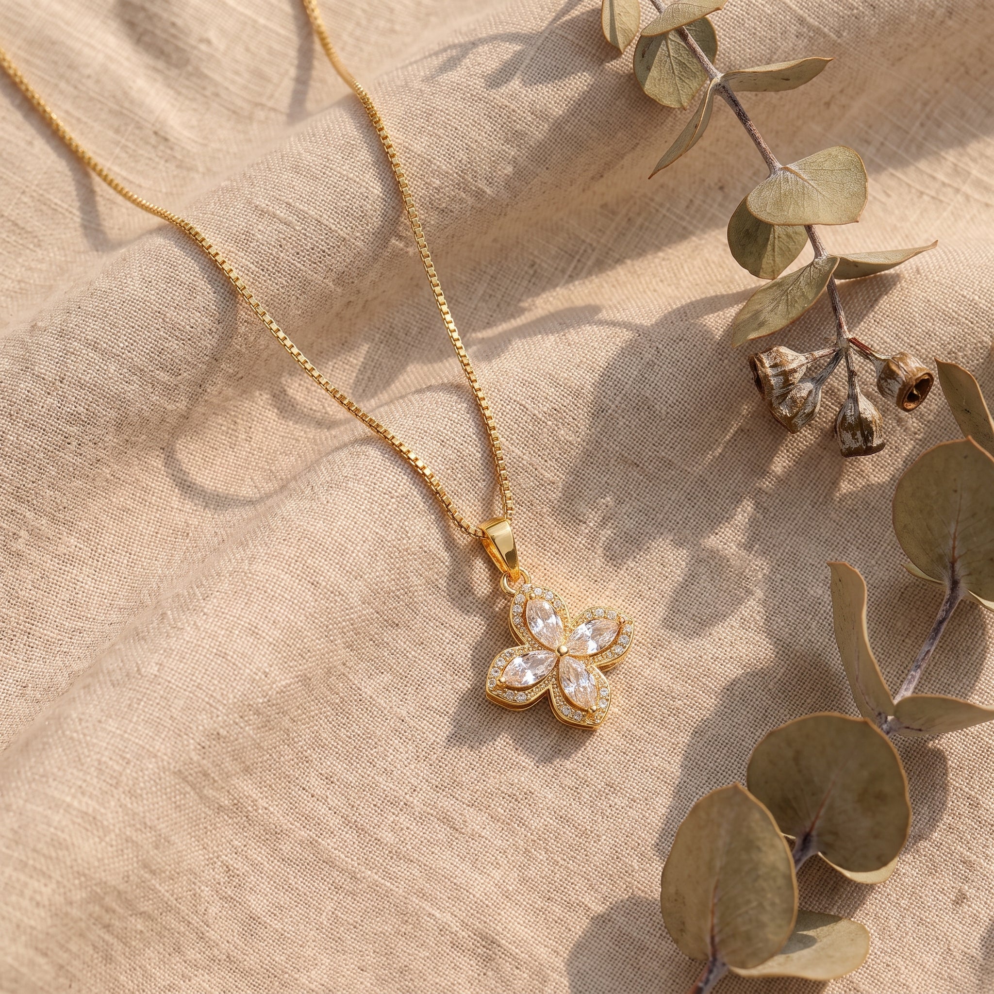 Gold flower pendant necklace on beige linen