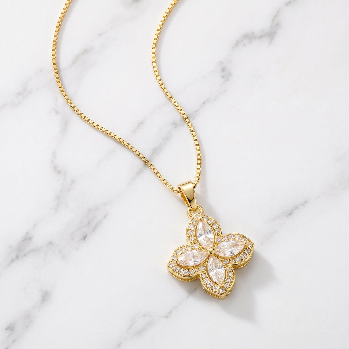 Gold flower pendant necklace on white marble