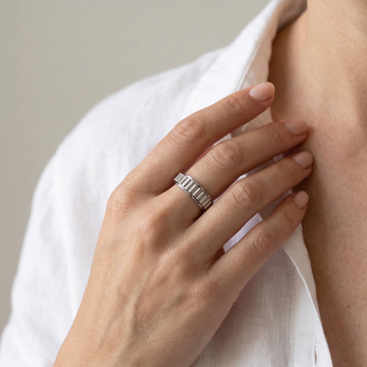 Hand at the collarbone wearing the Silver Grooved Spinning Ring