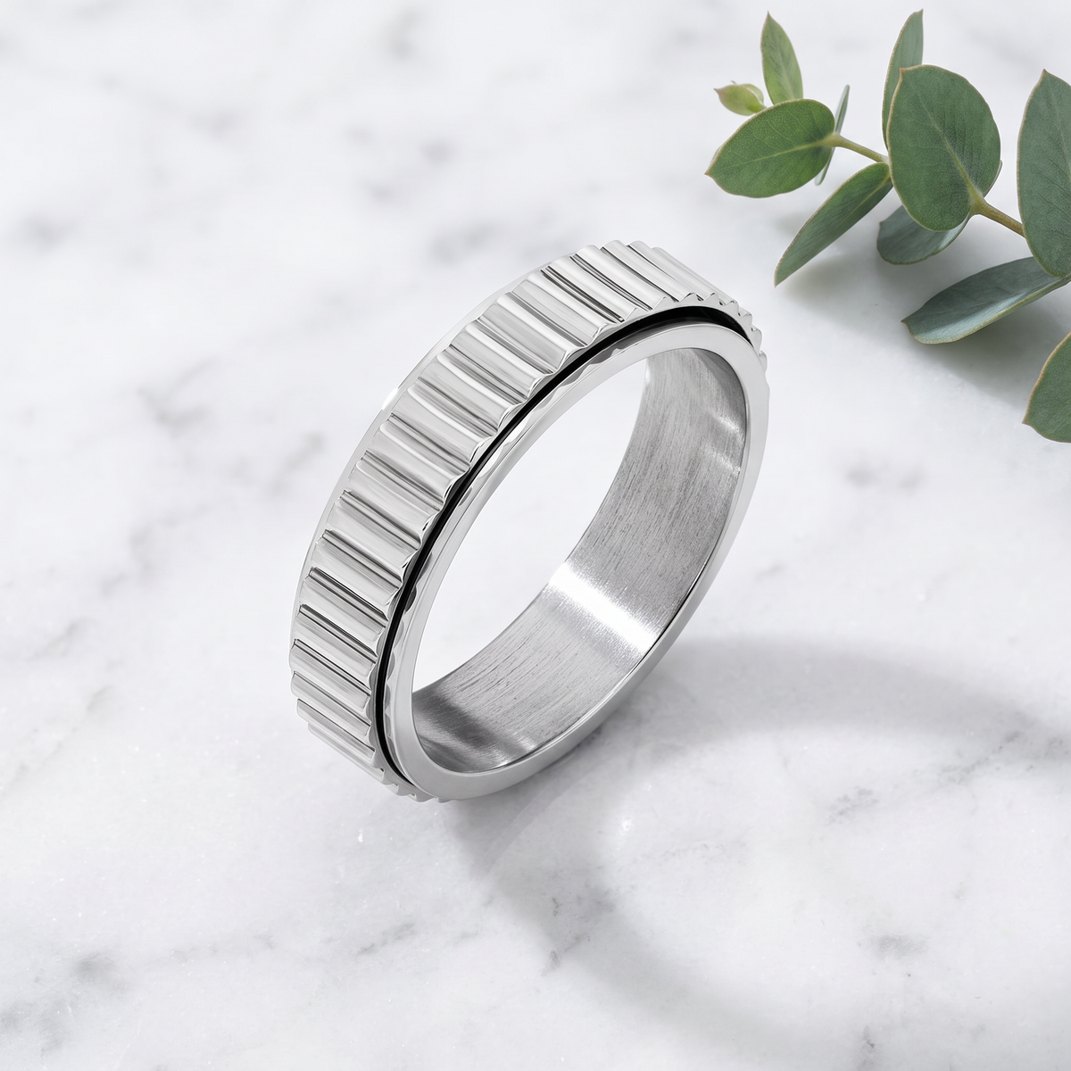 Silver Grooved Spinning Ring on white marble with eucalyptus