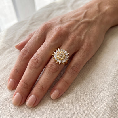 Hand wearing the gold crystal sunflower spinner ring on linen