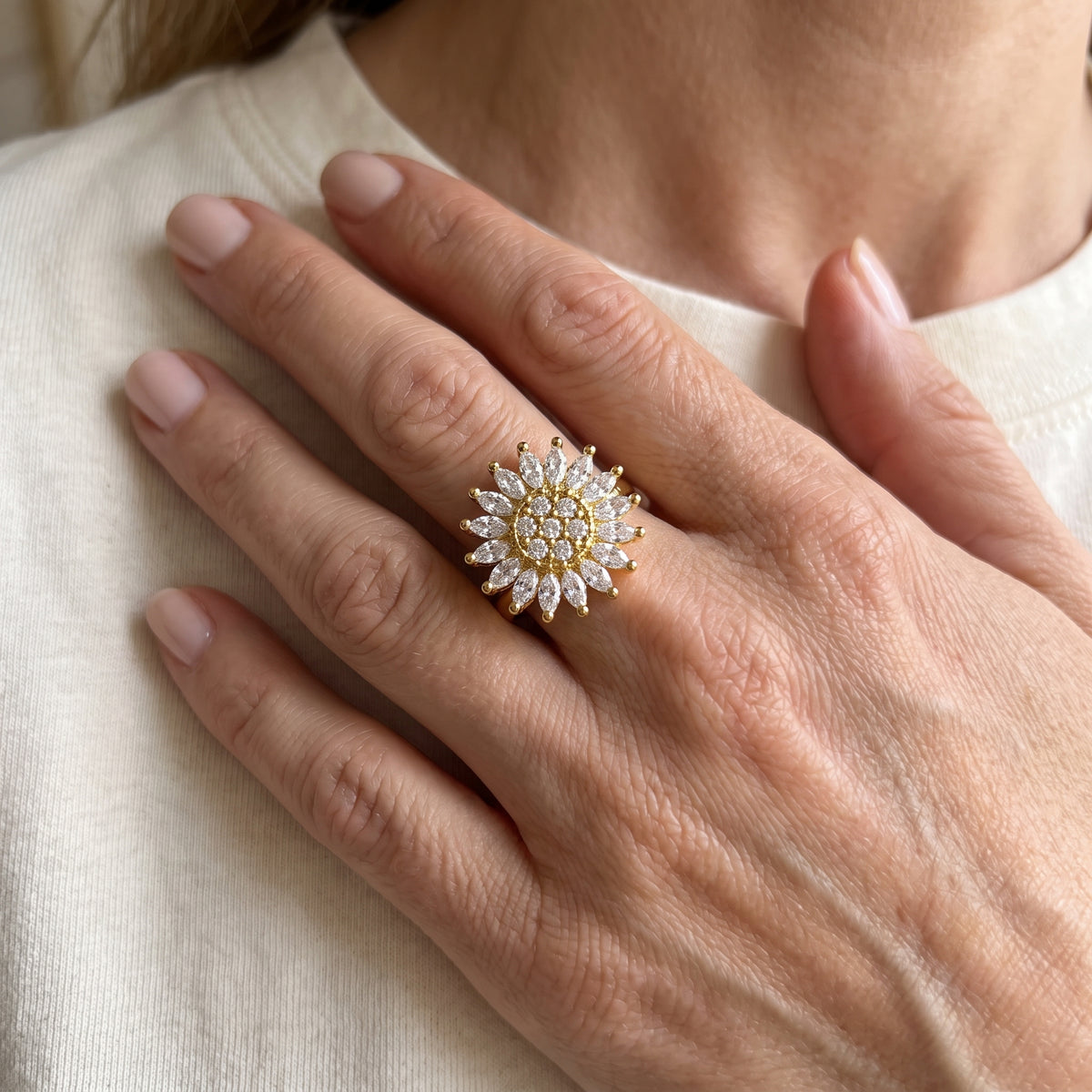 Sunflower spinner ring worn on the middle finger, hand at the collarbone