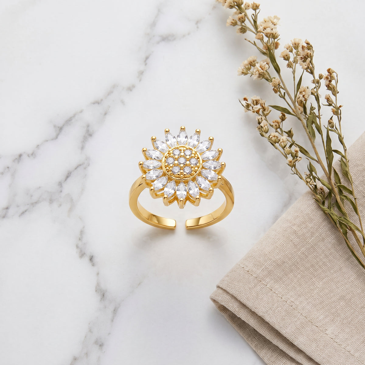 Gold open sunflower spinner ring on white marble
